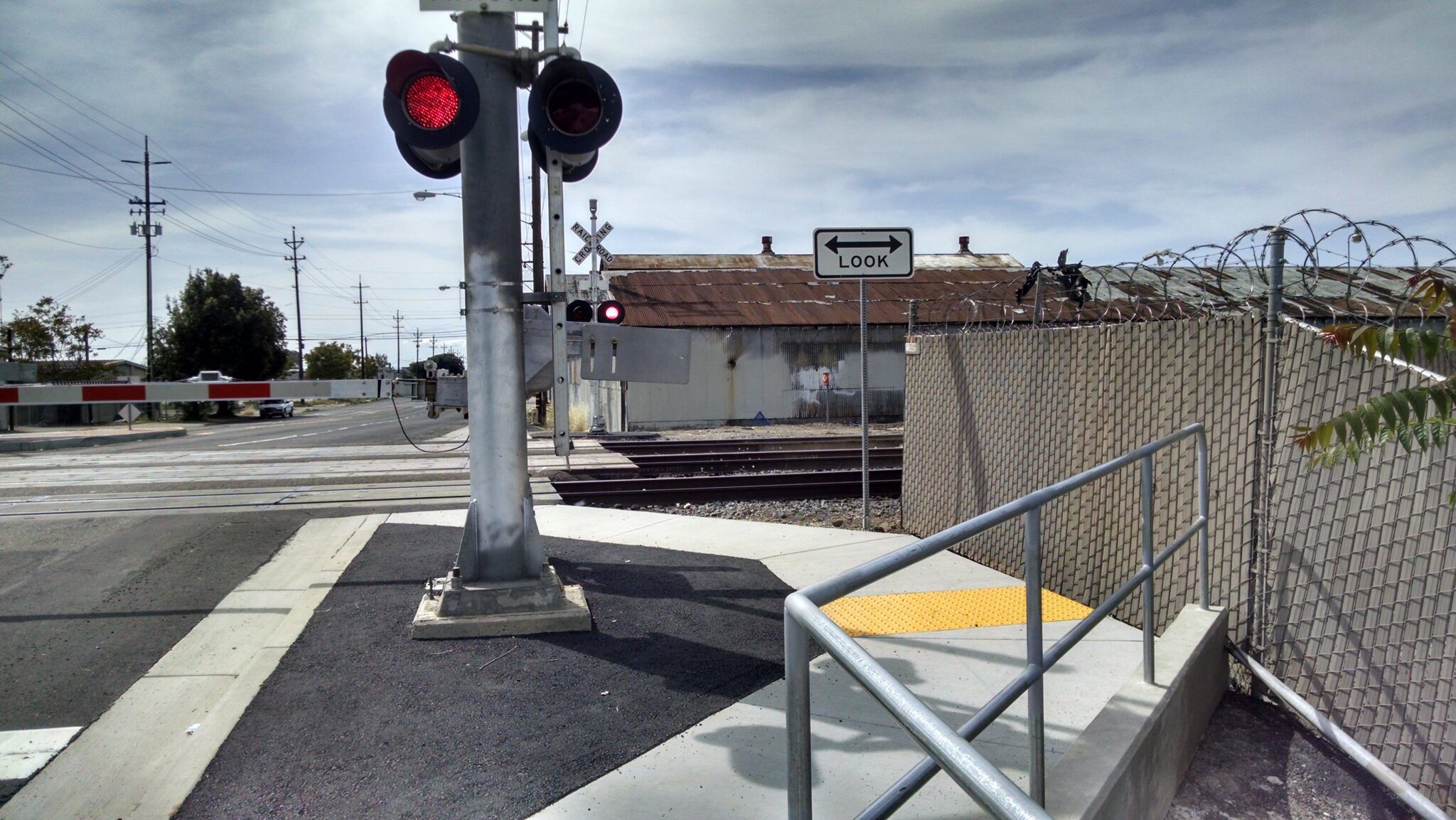 ADA compliant railway crossing. Active railroad crossing guard with lights in front of train tracks.